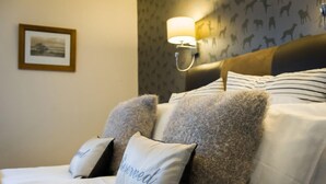 Une chambre d’hôtel avec un lit doté de draps à rayures et de deux oreillers moelleux, dont l’un porte le mot « Réservé ».
