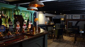 Un espace bar avec un comptoir en bois, diverses bouteilles et une carte accrochée au mur.