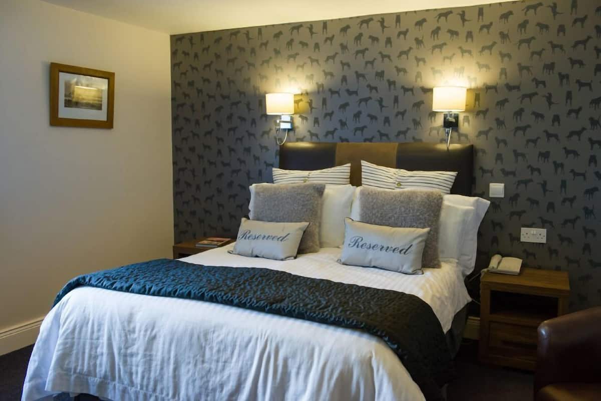 A hotel room with a bed, two bedside lamps, a nightstand, and a framed picture on the wall.
