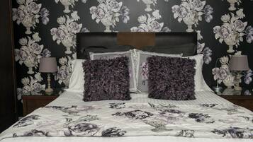 A bedroom with a floral-patterned bedspread, a headboard, and matching wall decor.