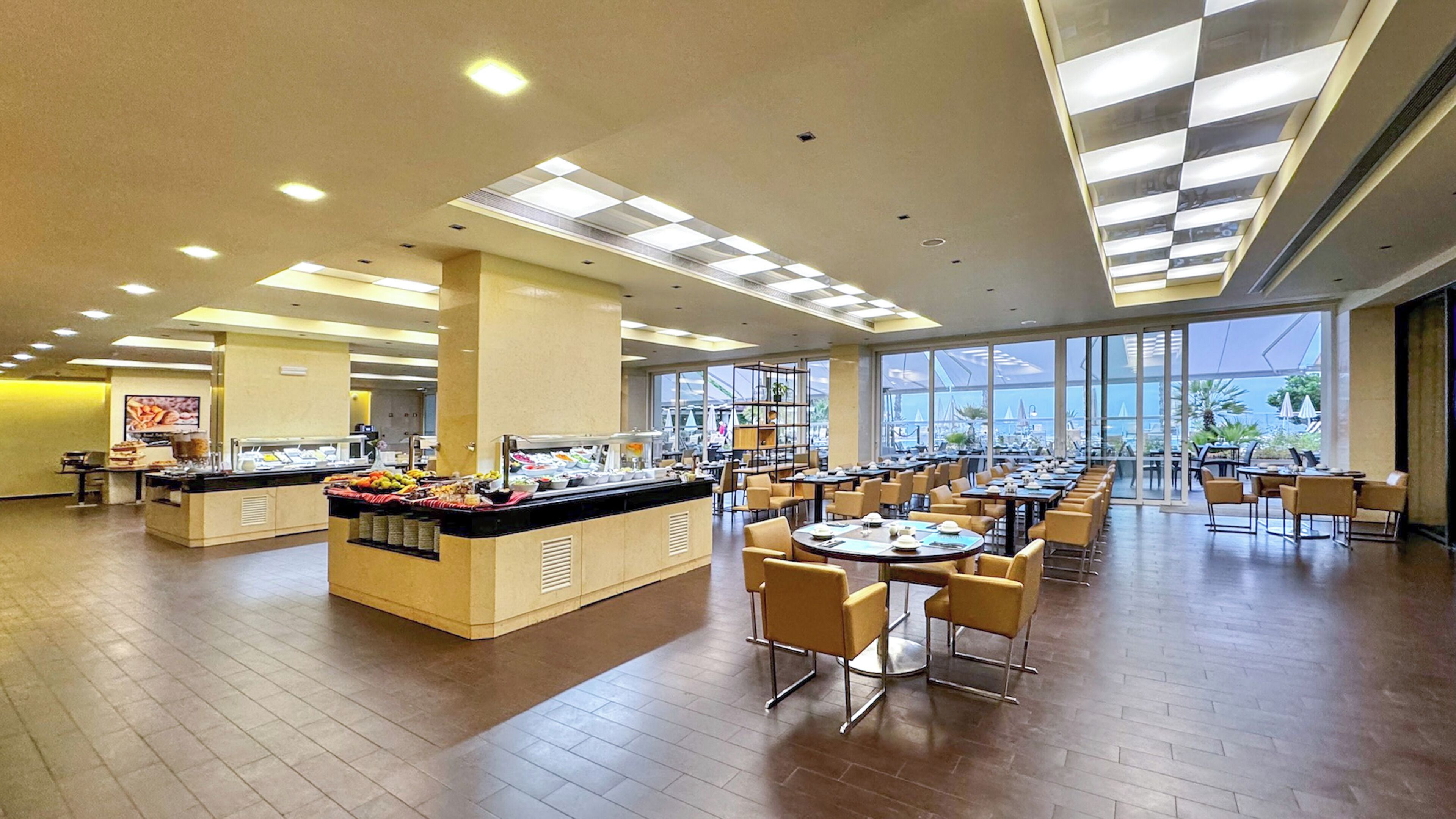 Un amplio comedor con un mostrador para buffet, varias mesas y sillas.