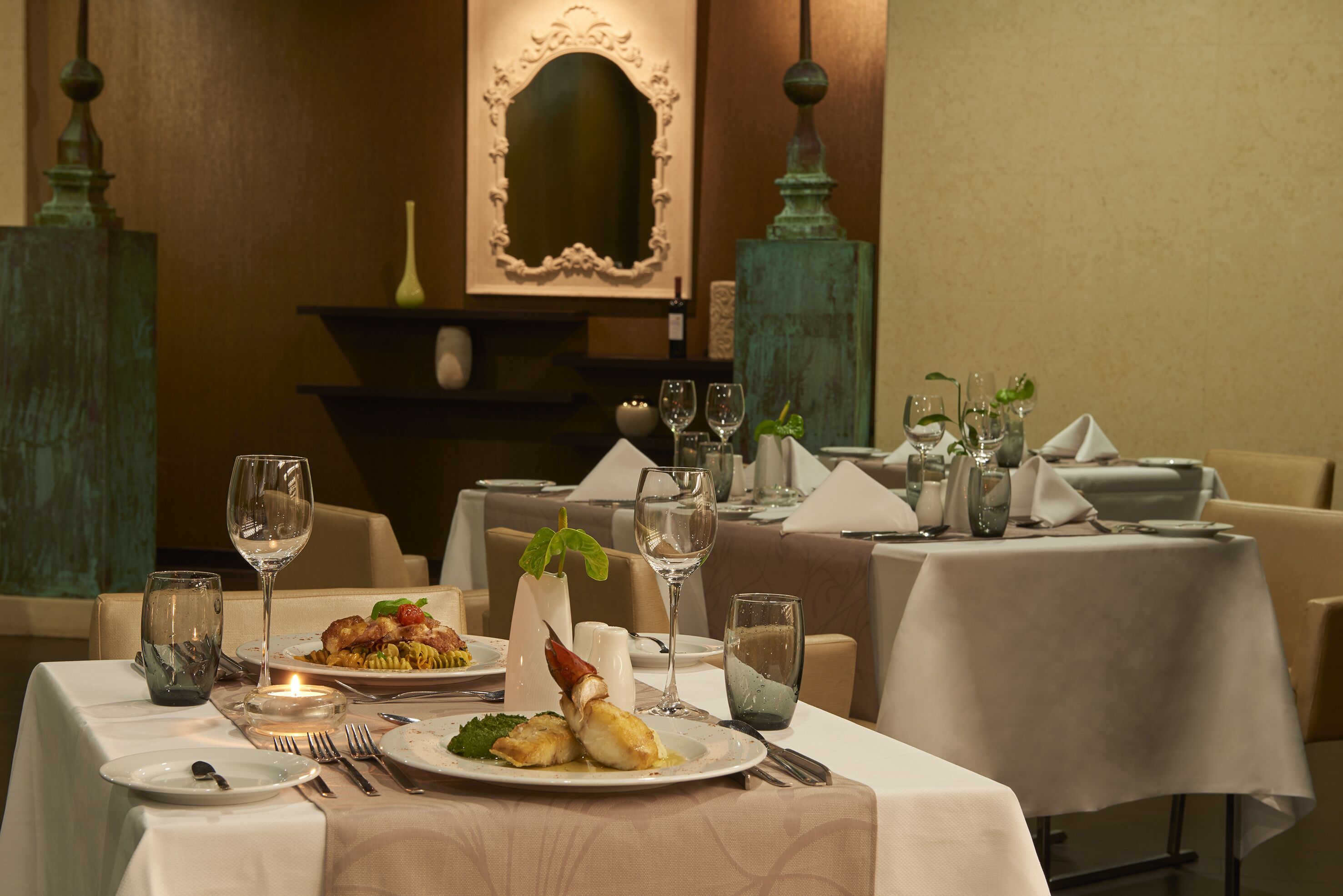 A dining table set with plates of food, wine glasses, and cutlery.