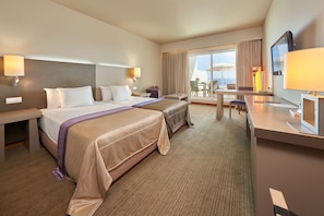 A hotel room with a large bed, a desk, a chair, and a television.