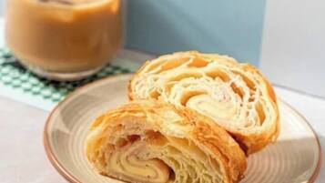 Two pastries on a plate with a glass of coffee in the background.
