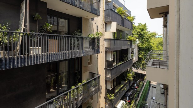 Un edificio residencial de varios pisos con balcones, algunos con plantas.