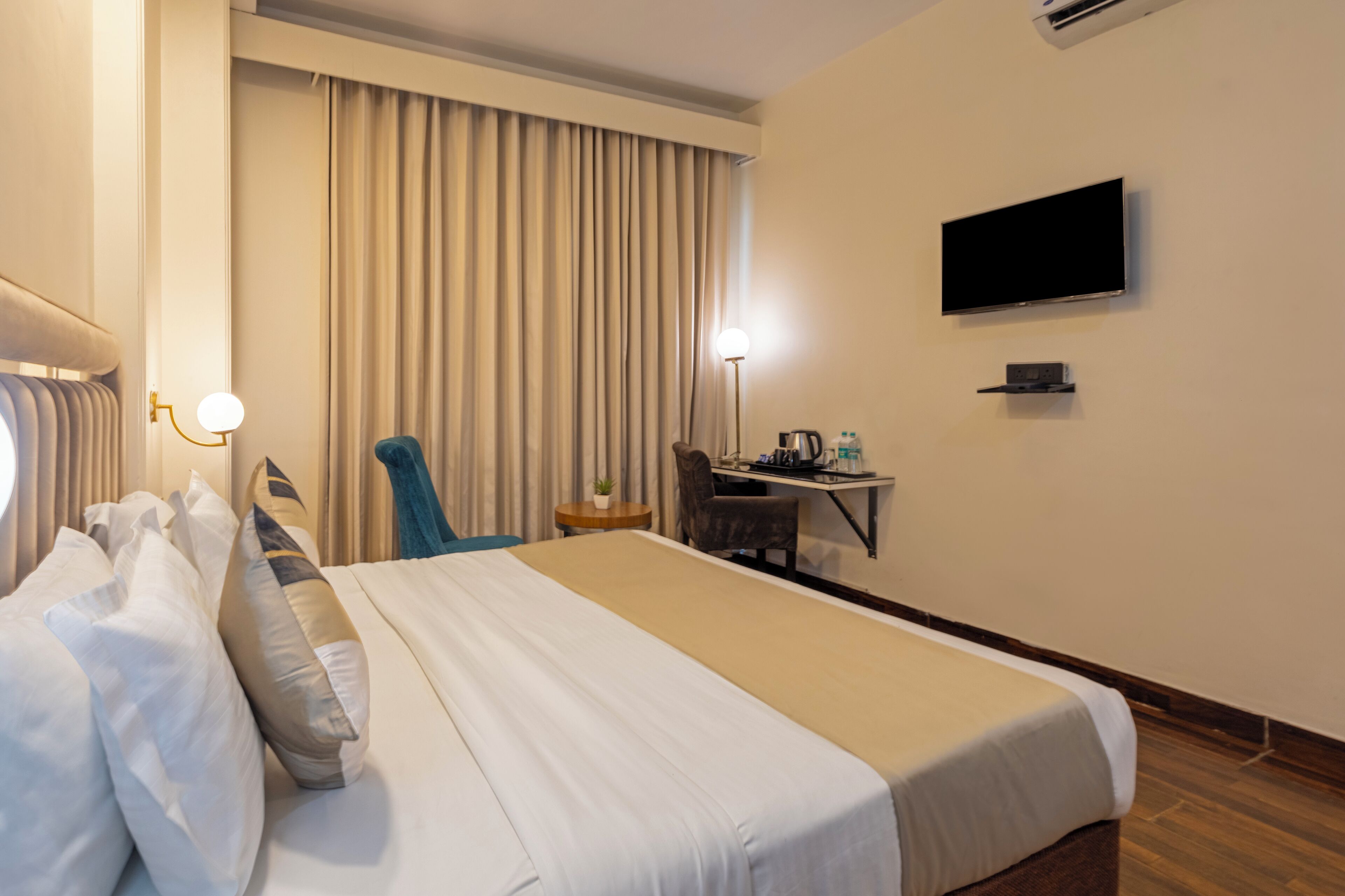 Een hotelkamer met een bed, bureau, stoel, televisie en gordijnen.