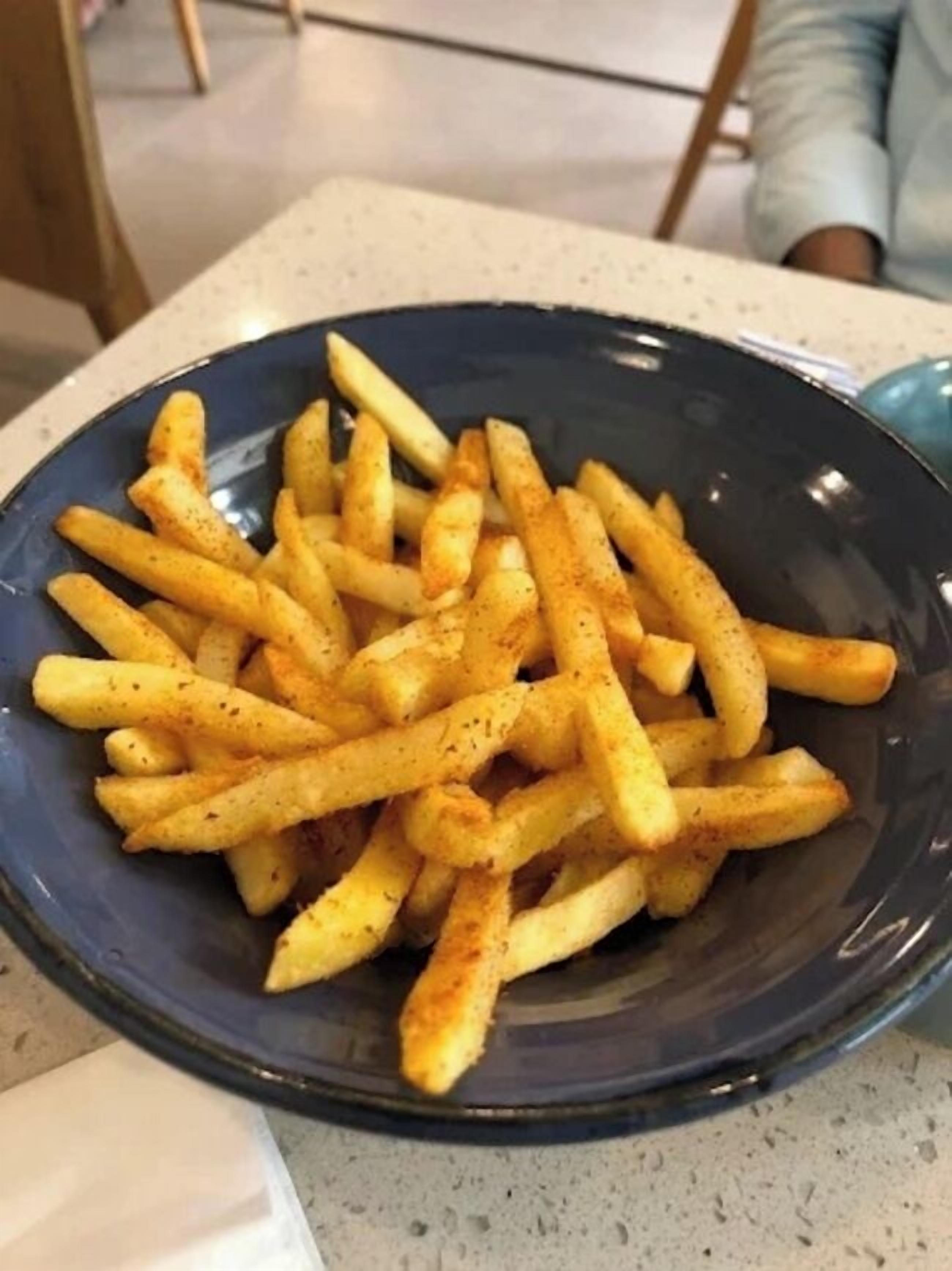 Un piatto di patatine fritte condite su un tavolo.