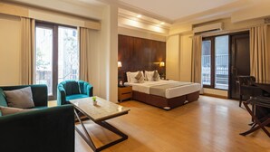 Habitación de hotel con cama, dos sillas, una mesita y balcón.