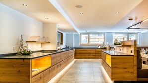 Una cocina moderna con armarios de madera, una isla central y abundante luz natural proveniente de amplias ventanas.