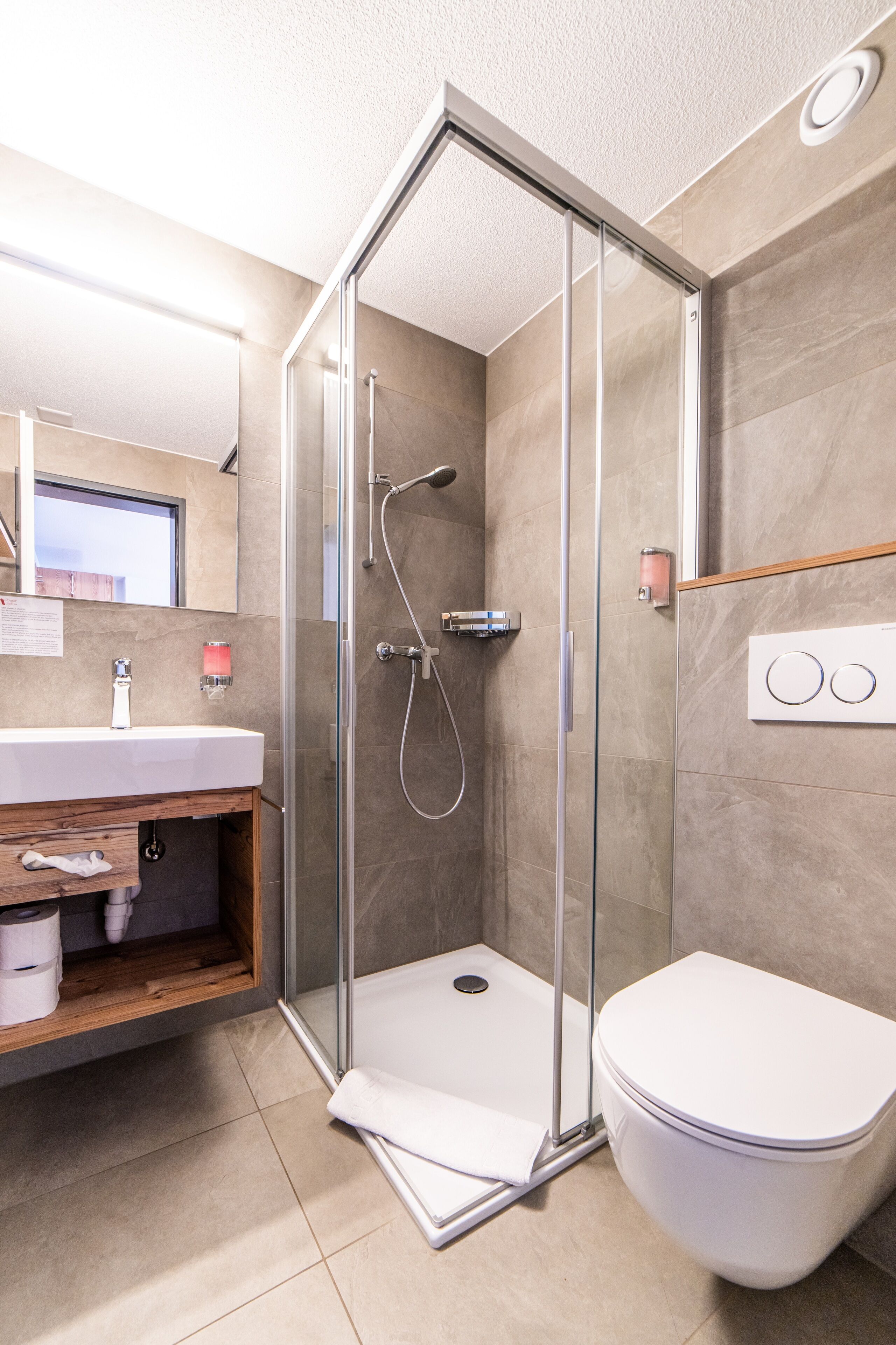 Une salle de bain moderne avec une douche à parois de verre, un lavabo blanc et des toilettes.