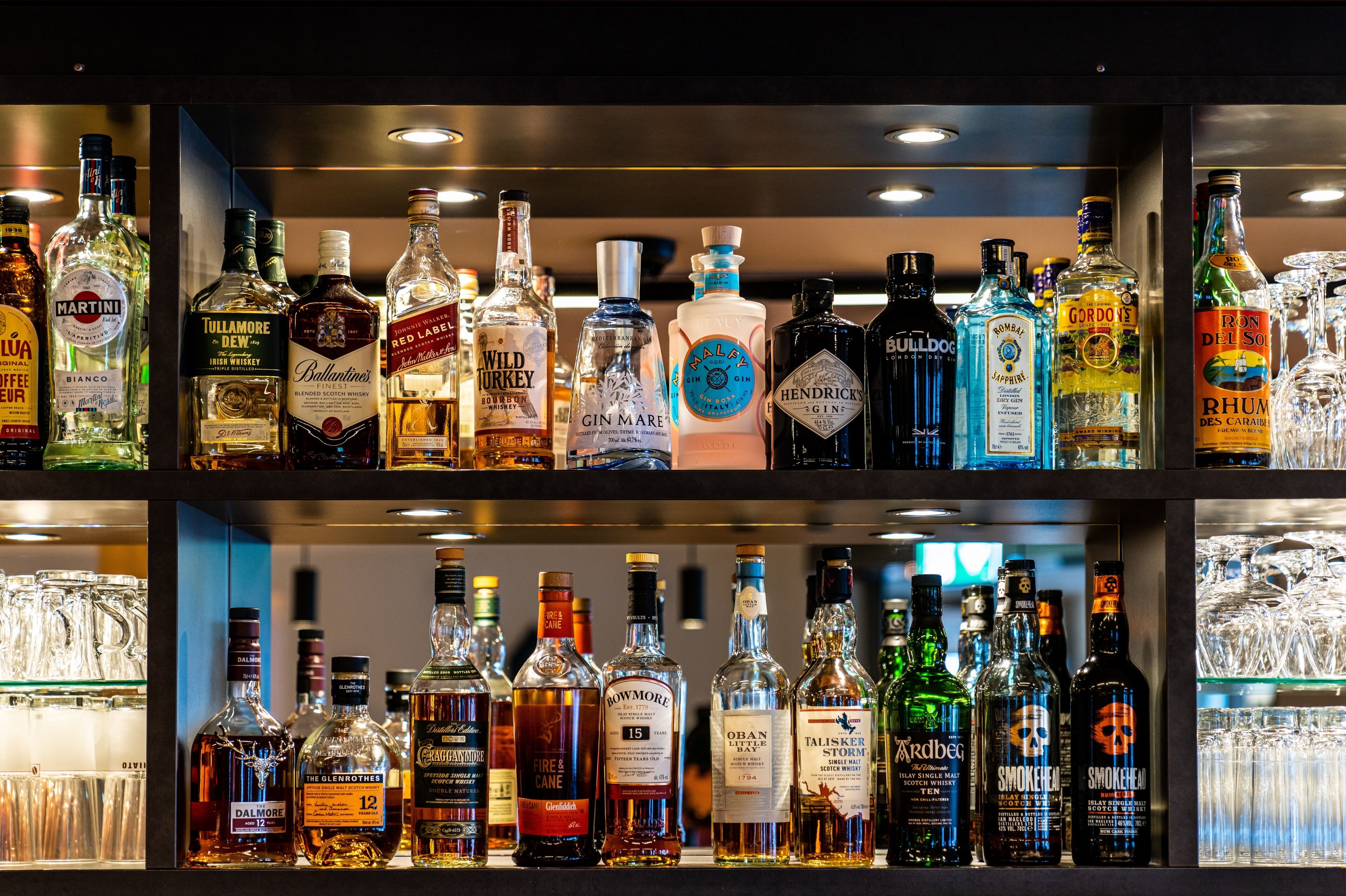 Um bar com diversas garrafas de bebidas e copos.
