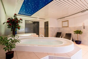 Un baño moderno con una bañera independiente grande, un techo con diseño de estrellas y plantas en macetas.