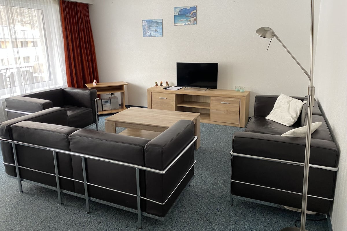 A modern living room with a sofa set, a coffee table, a TV, and a desk with a lamp.