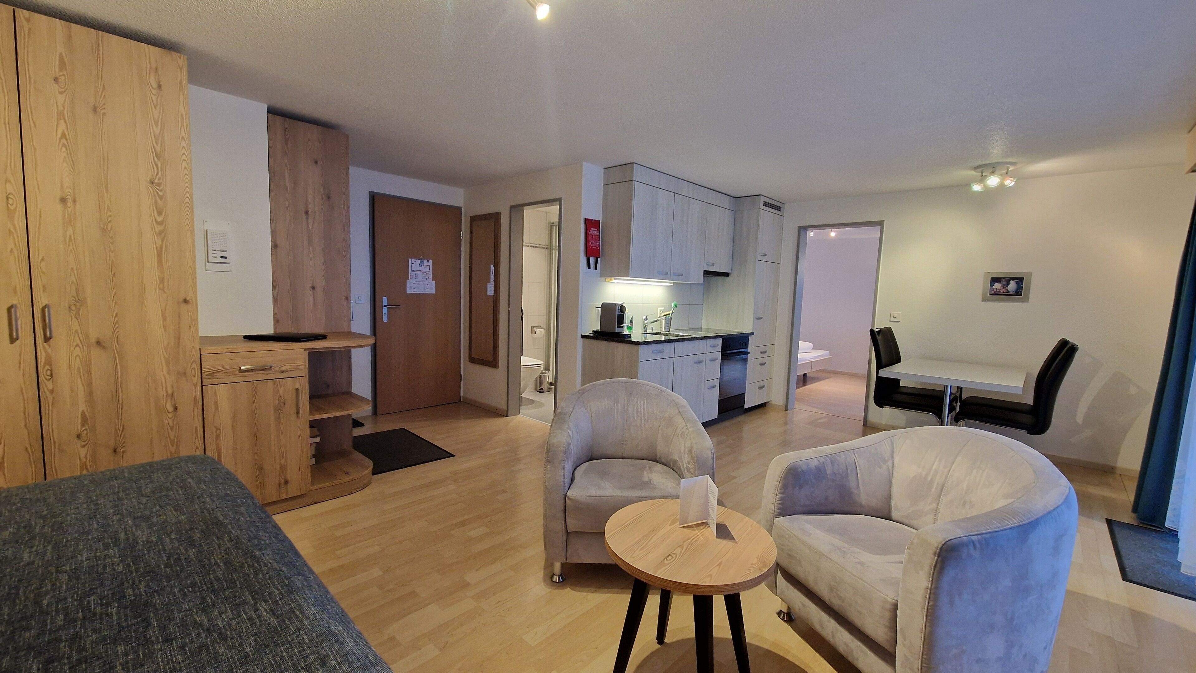 A compact living space with a kitchenette, a dining area, and a seating area with a small round table.