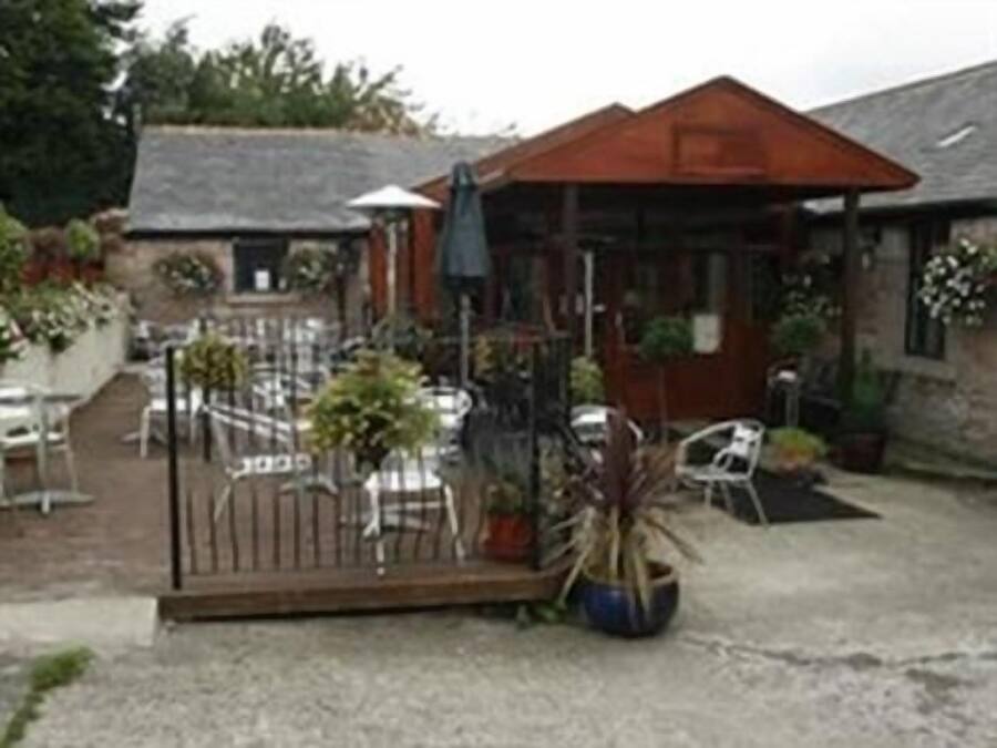 A courtyard with outdoor seating, a small building with a red roof, and potted plants.