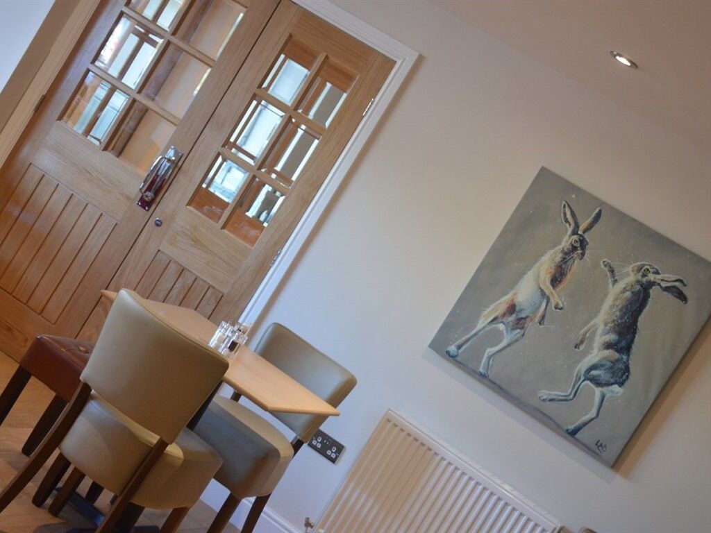 Een eetruimte met houten lambrisering, een tafel met stoelen en een schilderij van kangoeroes aan de muur.