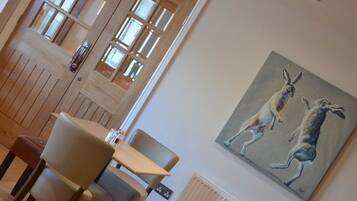 Een eetruimte met houten lambrisering, een tafel met stoelen en een schilderij van kangoeroes aan de muur.