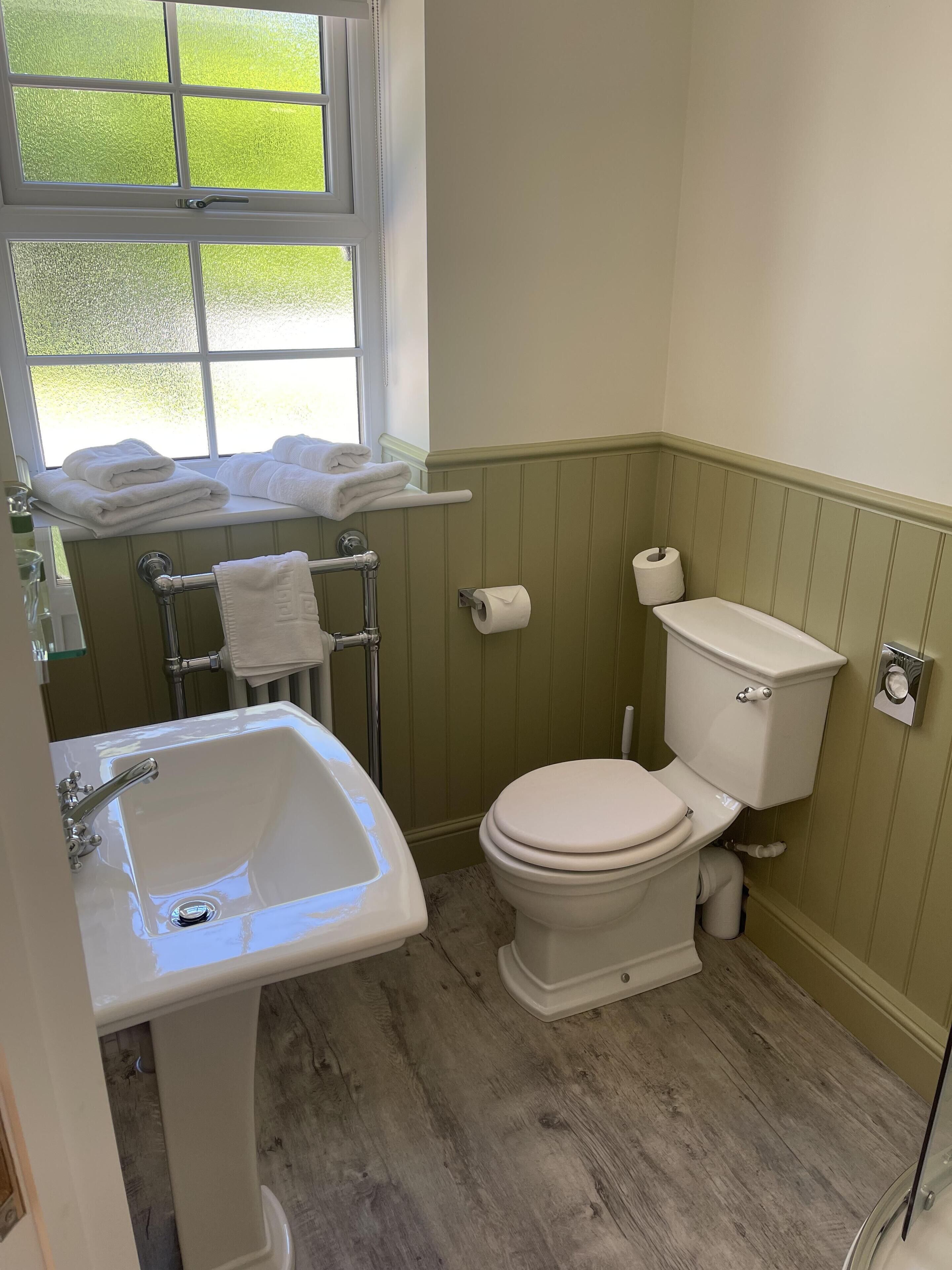 A bathroom with a sink, toilet, and window.