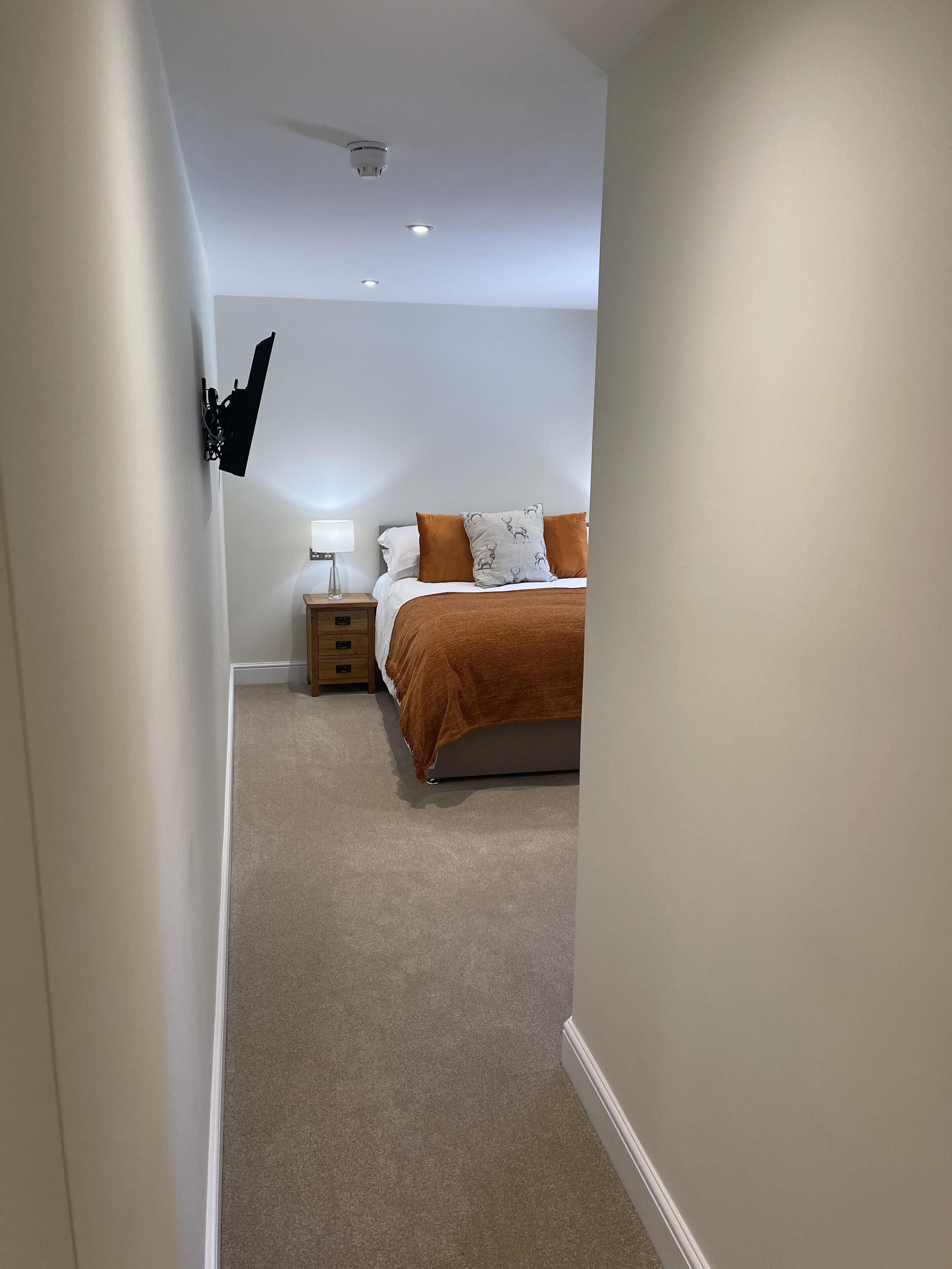 A bedroom with a bed, nightstand, lamp, and a ceiling fan.