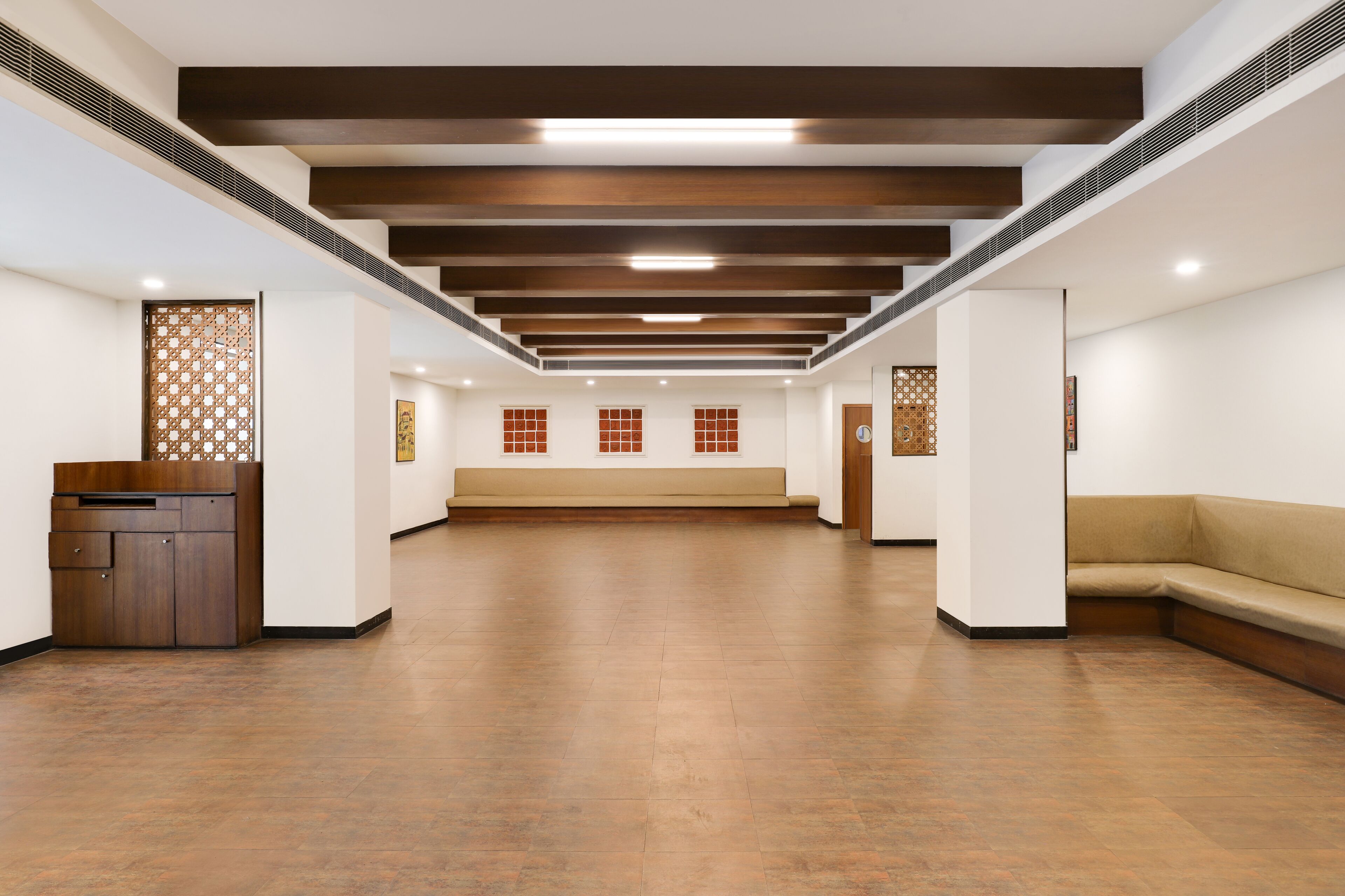 Um hall de hotel espaçoso com teto alto, vigas de madeira e uma área de estar central.