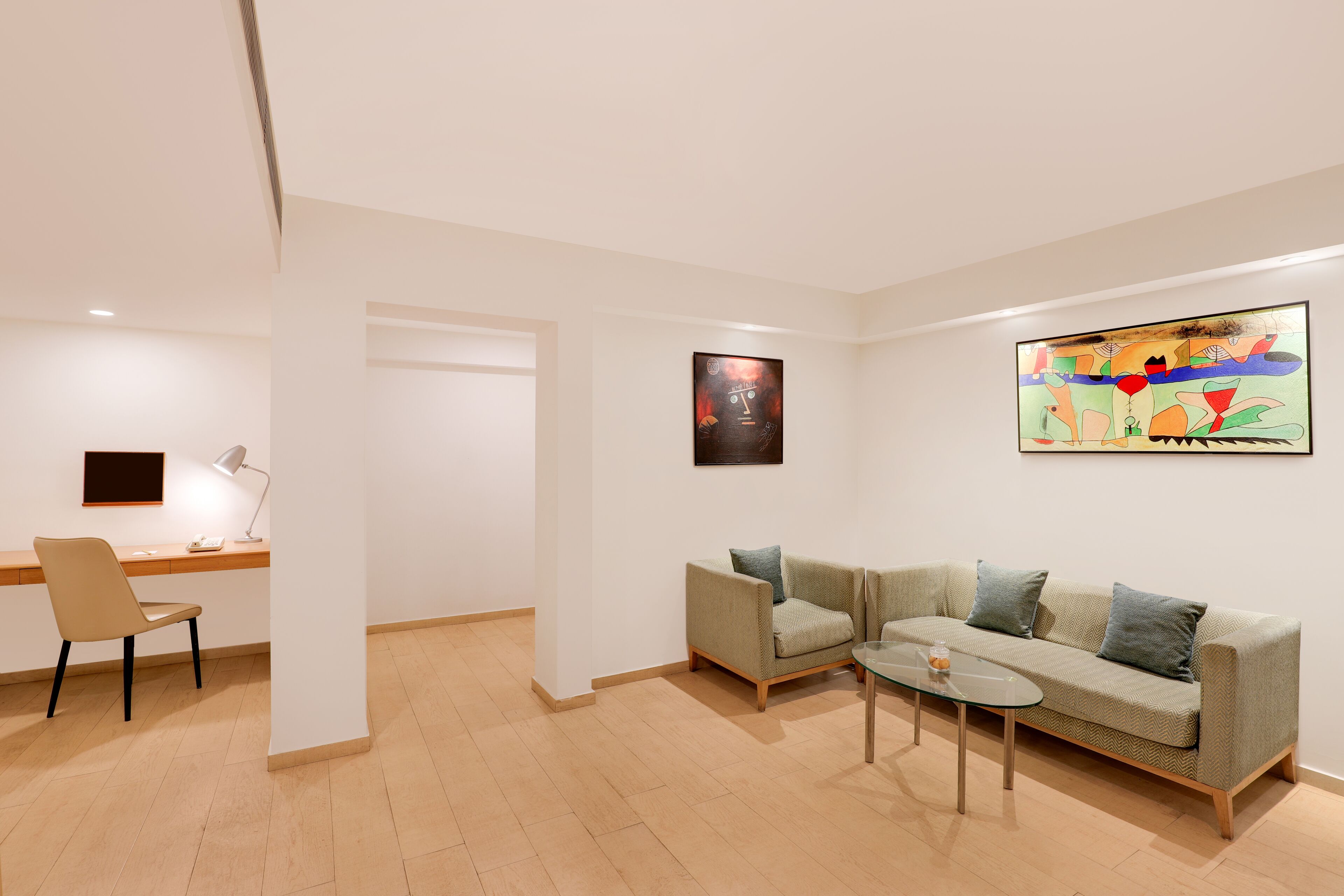 A modern living room with a sofa, a coffee table, and a desk with a chair.