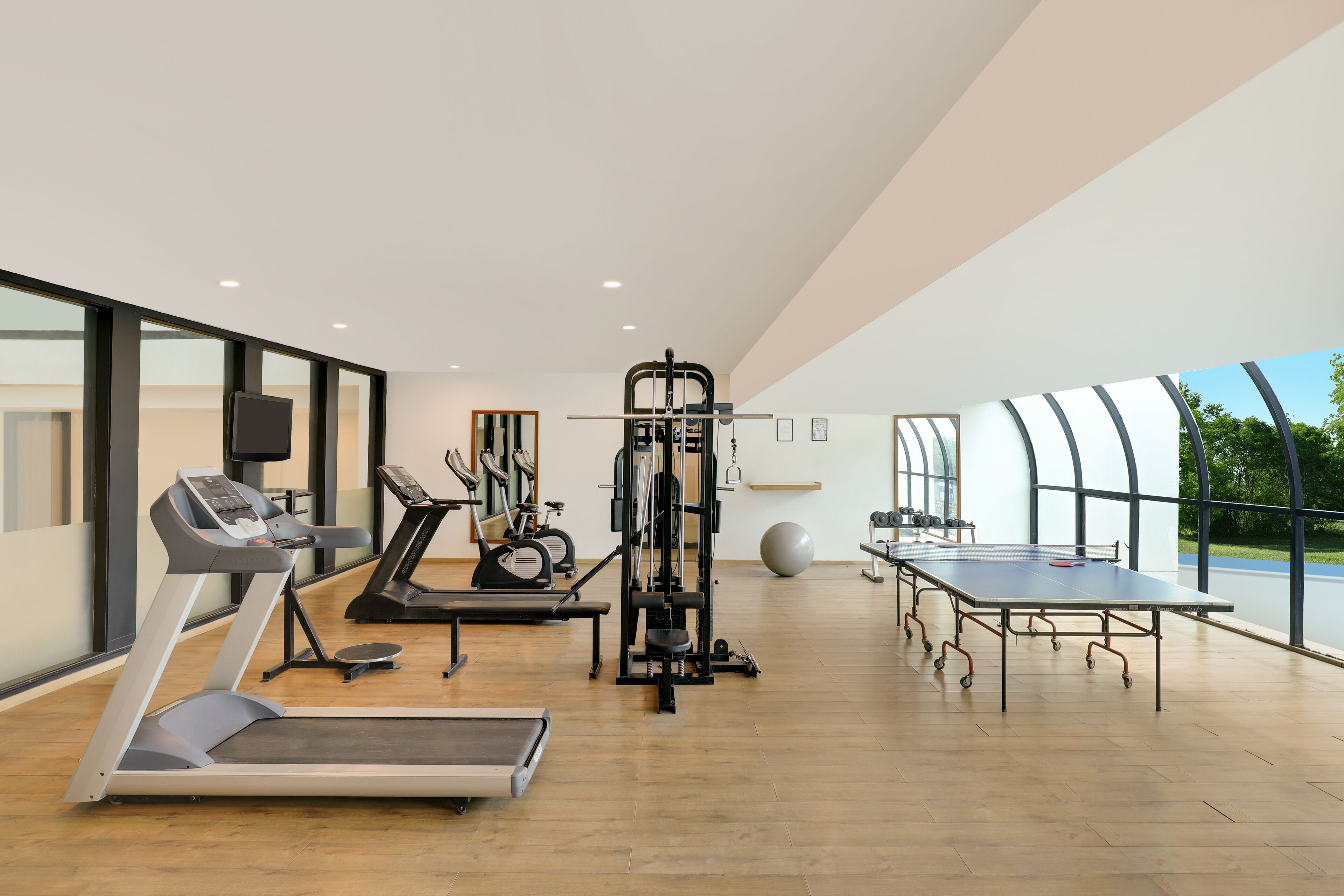 A modern gym with cardio equipment, weight machines, and a ping pong table.