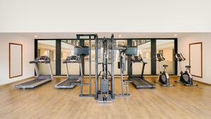 A gym with treadmills, elliptical machines, and a weight machine. - Lemon Tree Hotel, Indore (Indore)