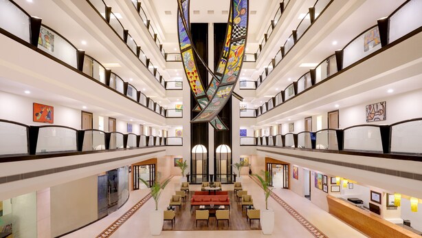 A spacious hotel lobby with a central seating area, multiple floors with balconies, and artwork on the walls. - Lemon Tree Hotel, Indore (Indore)