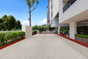 A modern building with a courtyard, featuring a white exterior, red accents, and green landscaping.