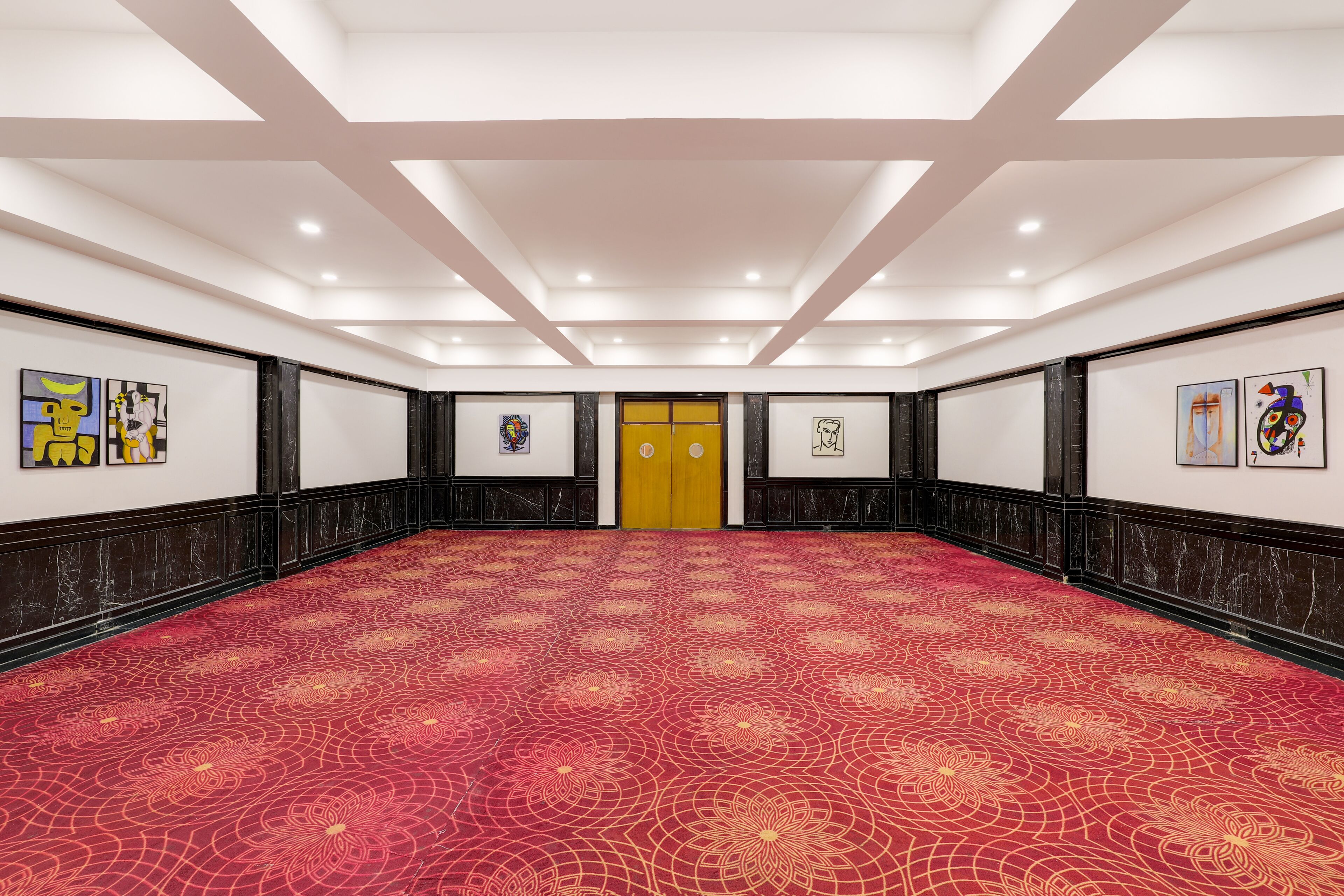 A conference room with a red patterned carpet, white walls, and black wainscoting.