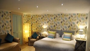 A bedroom with a bed, two bedside tables, a chair, and a door. - The Black Swan (Kirkby Stephen)