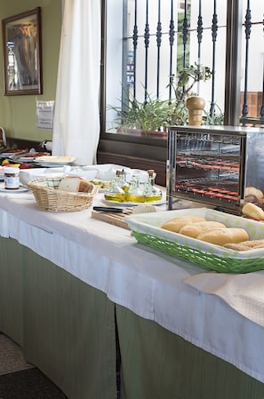 A buffet table with various food items, a bread basket, condiments, and a bread box. - Hotel y Bungalows Balcón de Competa (Còmpeta)