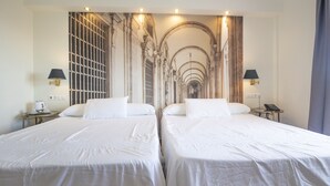 Een hotelkamer met twee bedden, een grote muurschildering en twee nachtkastjes met lampen.