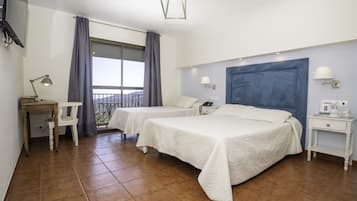 Una habitació d'hotel amb dos llits, un escriptori, una cadira, una tauleta de nit, una làmpada i vista a l'exterior.