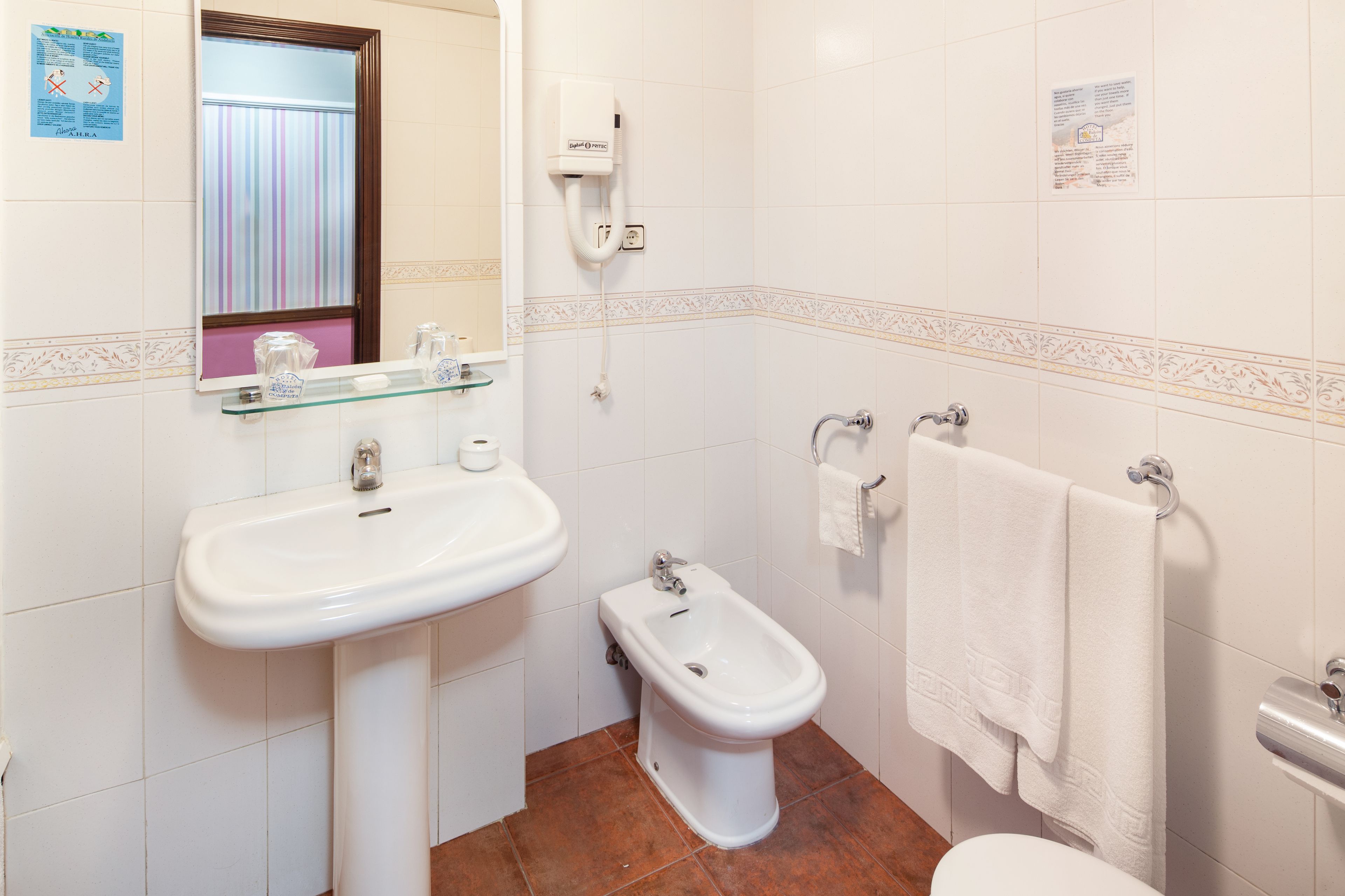Un baño con lavamanos, bidé y toallero.