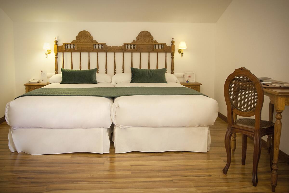 A double bed with a wooden headboard, two bedside tables with lamps, and a wooden chair.