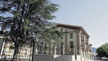 A building with a classic architectural style, featuring a symmetrical facade, multiple windows, and a prominent entrance with a decorative iron gate.