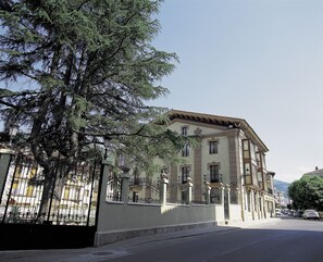 Un edificio de estilo arquitectónico clásico, con fachada simétrica, múltiples ventanas y una entrada destacada con una reja decorativa de hierro.