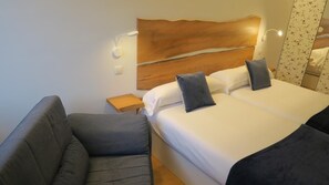Une chambre d’hôtel avec un grand lit, deux oreillers, une table de chevet et une chaise.