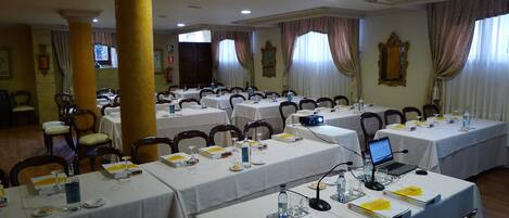 A conference room with multiple tables, chairs, and laptops, equipped with nameplates and water bottles.