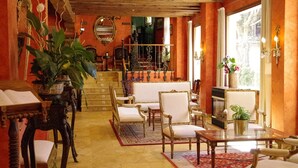Un salón amplio con chimenea, asientos cómodos y una planta grande.
