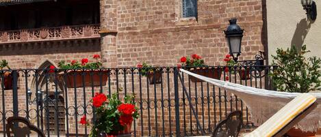 Un patio con una mesa y sillas, una hamaca, y un edificio de ladrillo con una torre de campanas al fondo.