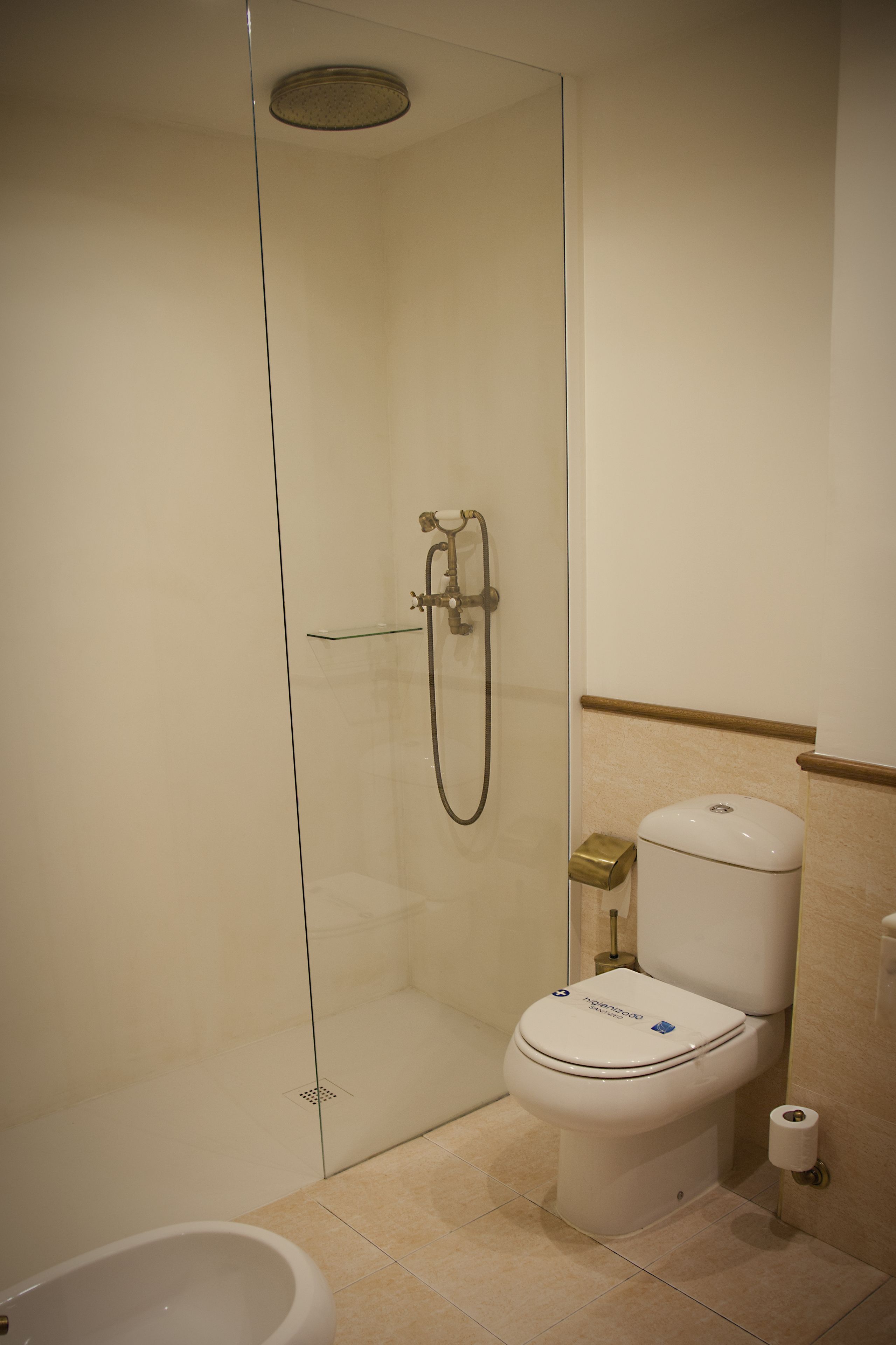 Un baño moderno con ducha envuelta en vidrio, inodoro blanco y bañera blanca.
