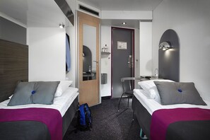 A hotel room with two beds, a desk, a chair, and a bathroom door. - CABINN Express Hotel (Frederiksberg)