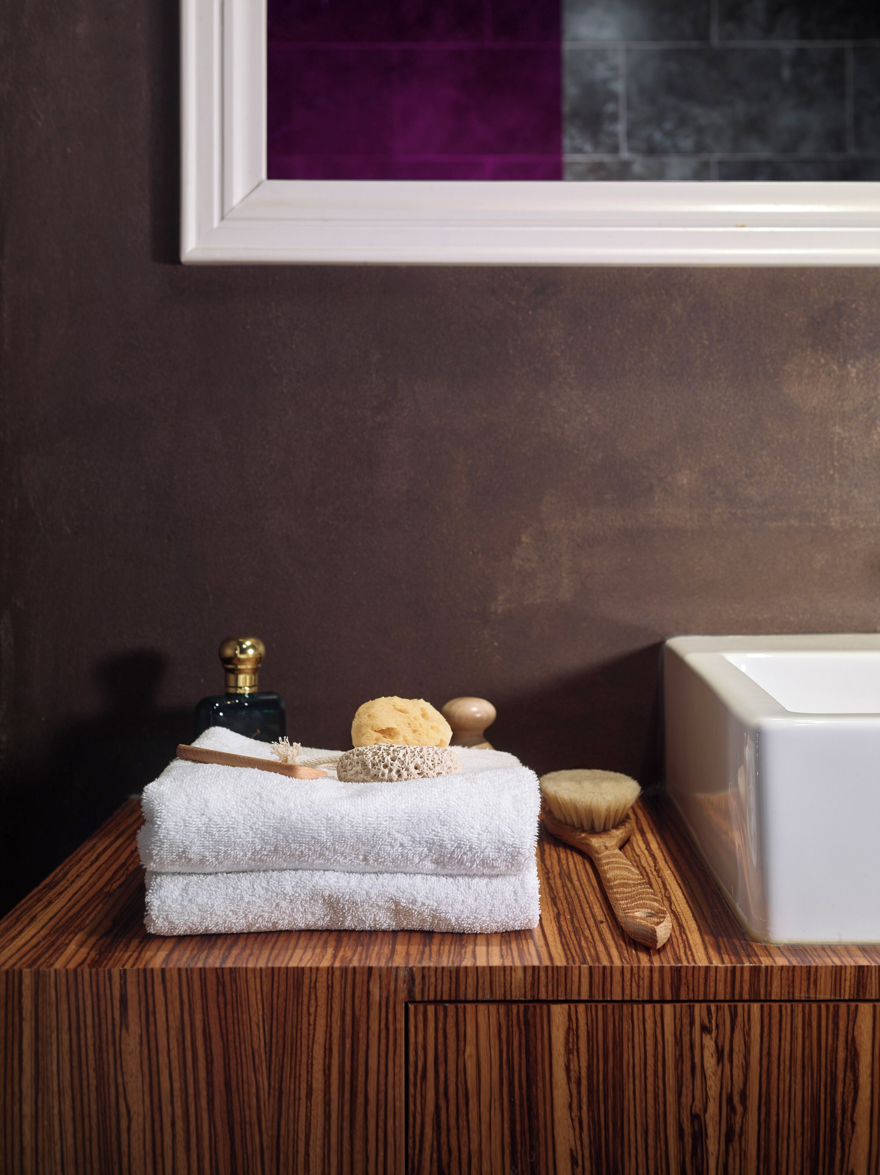 Een houten wastafel met een witte handdoek, een fles, een zeepstuk en een houten borstel.