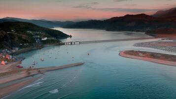 A coastal landscape with a bridge, calm waters, and a distant shoreline.