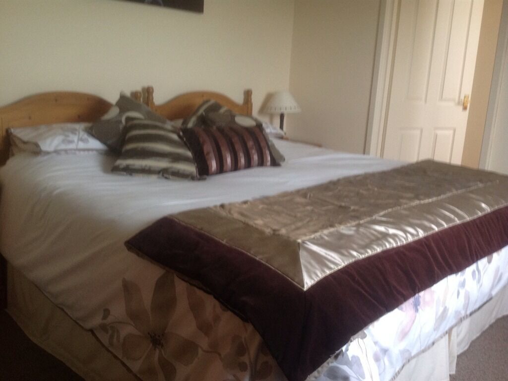 A neatly made bed with a floral-patterned bedspread and a dark throw blanket.