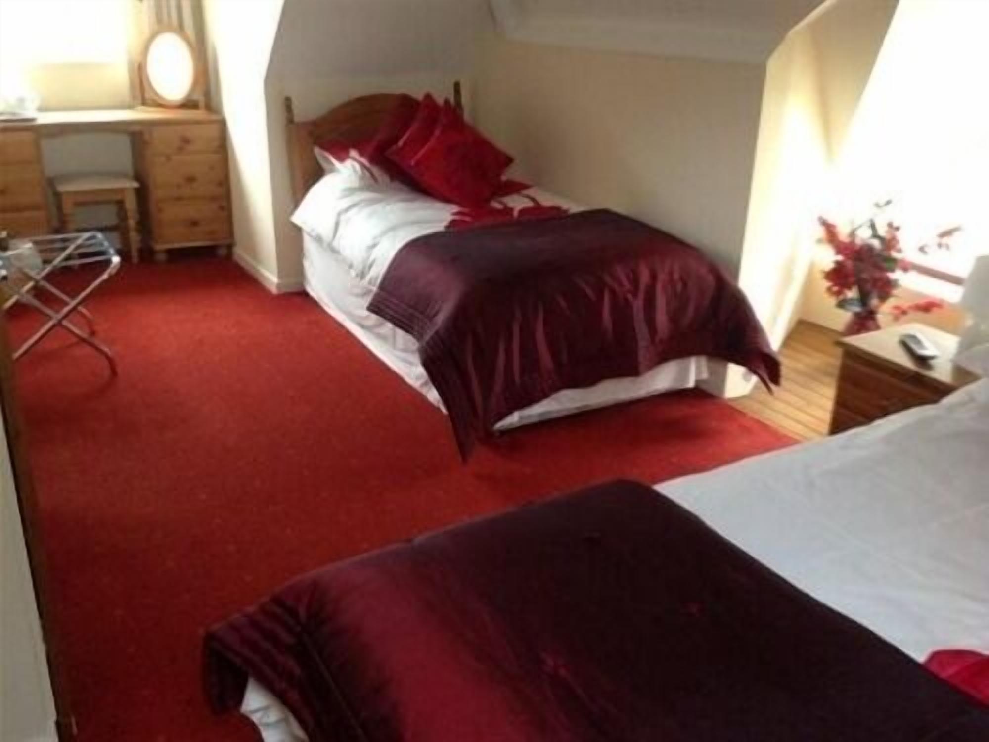 A bedroom with two beds, a desk, and a chair.