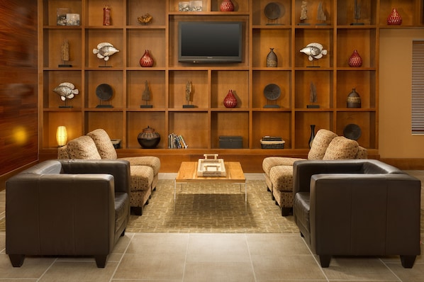 A living room with a flat-screen TV, two sofas, a coffee table, and a wooden shelving unit with decorative items.