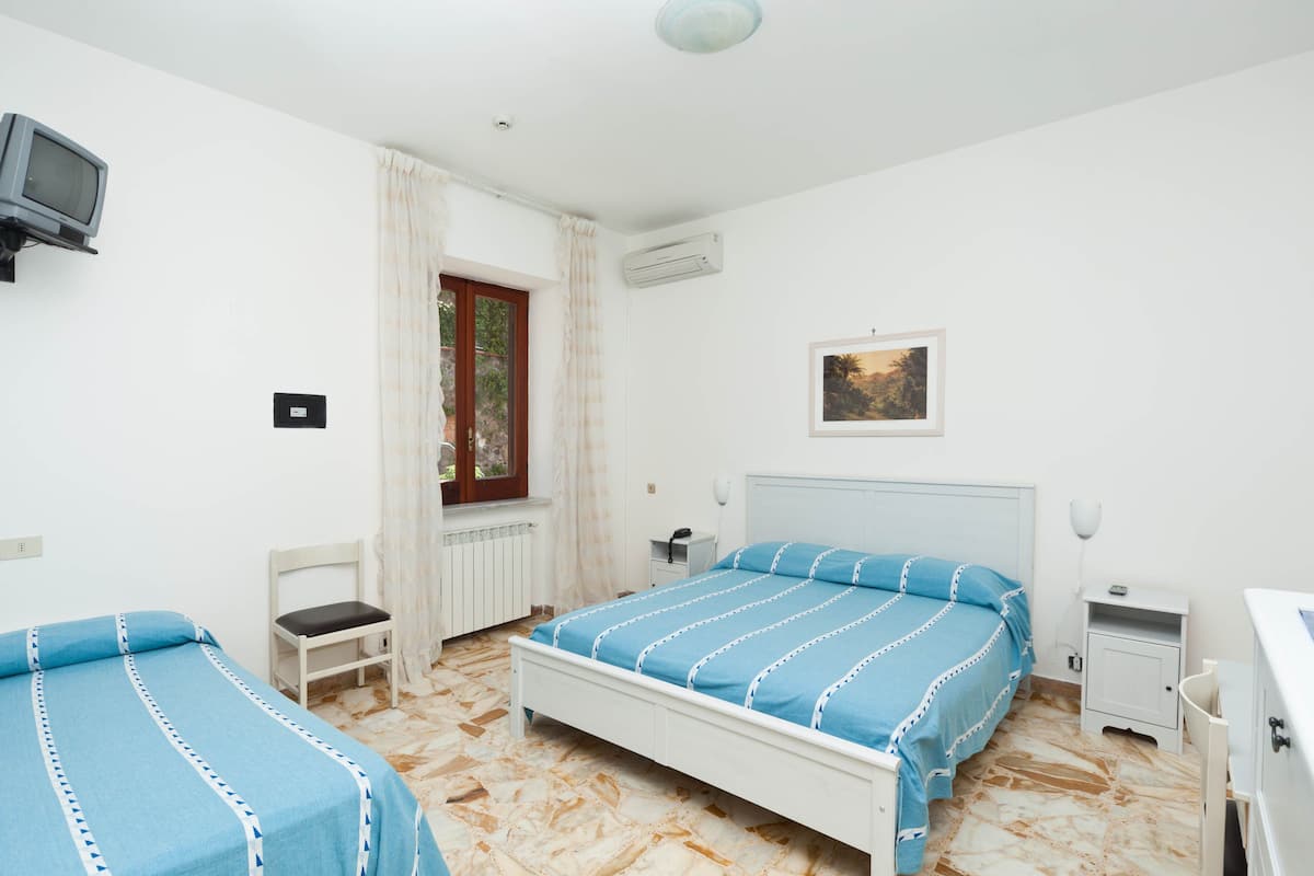 Een slaapkamer met een bed, een stoel, een klein tafeltje, een nachtkastje en een televisie.